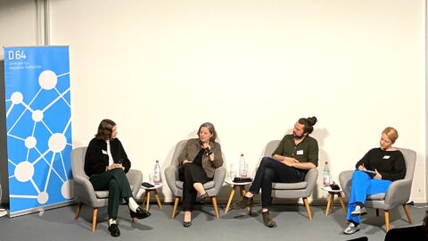 Elisabeth Nöfer, Regine Grienberger, Tobias Bacherle und Elisa Lindinger im Gespräch. Links neben ihnen ein Rollup mit D64-Branding.